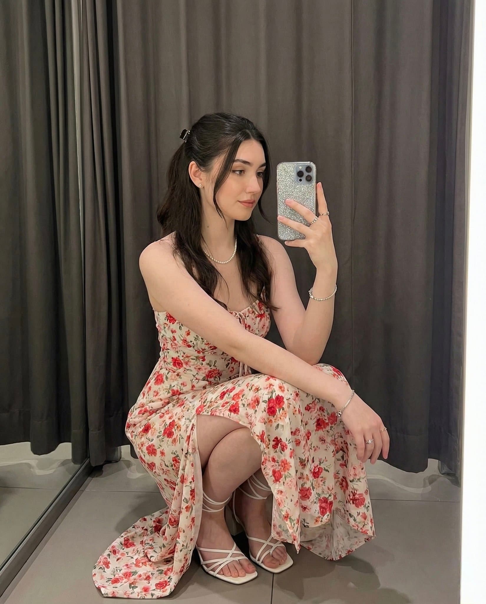 A young woman elegantly crouches indoors for a selfie.